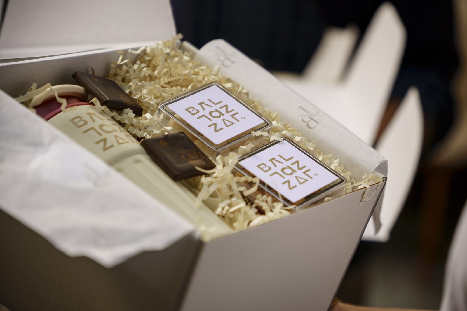 Detalhe do kit de brindes da BALTAZZAR aberto sobre a mesa, com bombons e brindes personalizados da marca